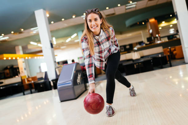 centrado feliz mujer disfrutando de bolos - bowling holding bowling ball hobbies fotografías e imágenes de stock