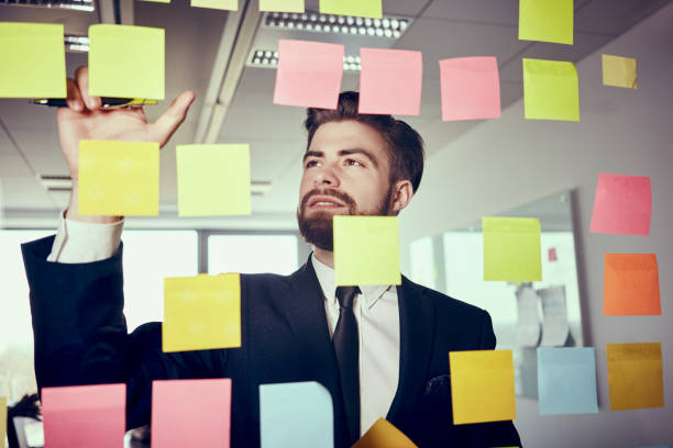 istock Creative businessman working with stocky notes on glass wall in office 1032539084