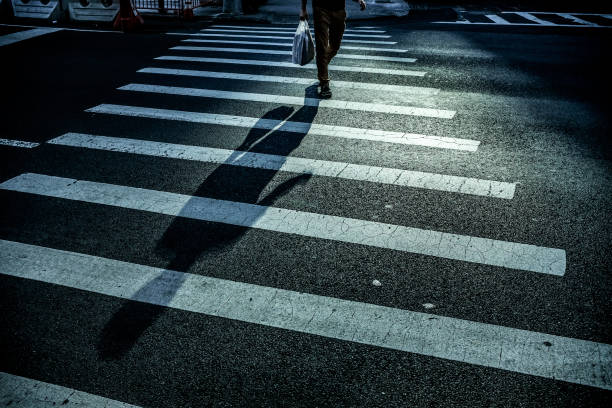 istock Man with long shadow crossing the street 1032548210