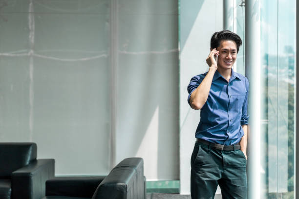 istock Smiling businessman talking on phone by window 1032551808