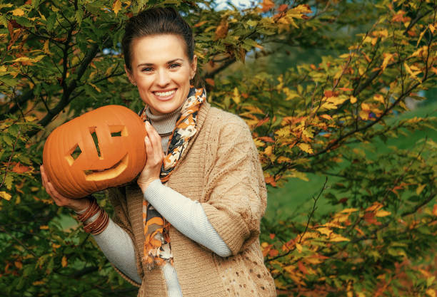 istock happy woman showing Halloween pumpkin Jack O'Lantern 1032551846