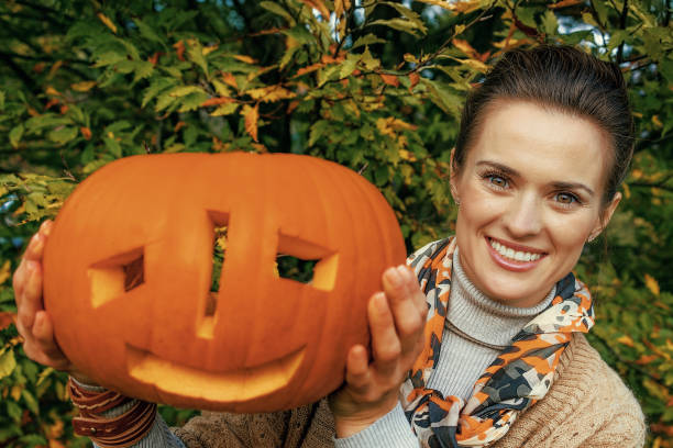 istock woman showing carved Halloween pumpkin 1032551864
