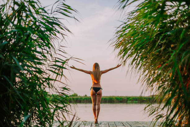 istock Young woman in bikini on pier by river 1032553134