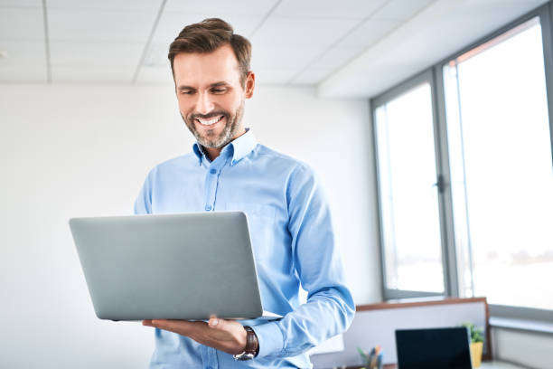 istock Happy business worker standing in office with laptop 1032553636
