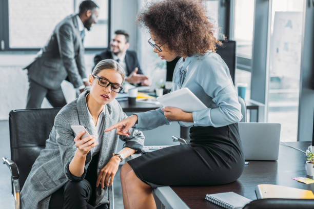 istock multicultural businesswomen looking at smartphone in office 1032560336