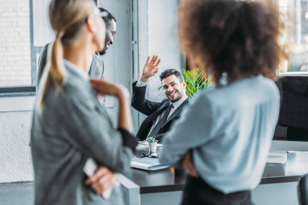 istock smiling businessman waving hand to multicultural colleagues in office 1032560368