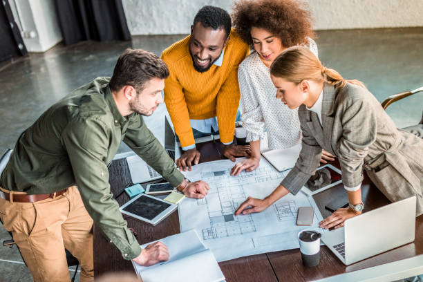 istock high angle view of multicultural businesspeople with blueprint in office 1032561638