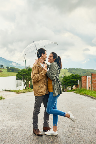 Cropped shot of a loving couple standing outside with an umbrella