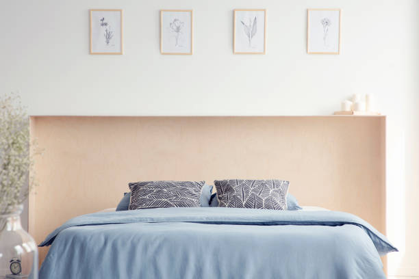istock Patterned pillows on blue bed in minimal white bedroom interior with posters and plant. Real photo 1032582164