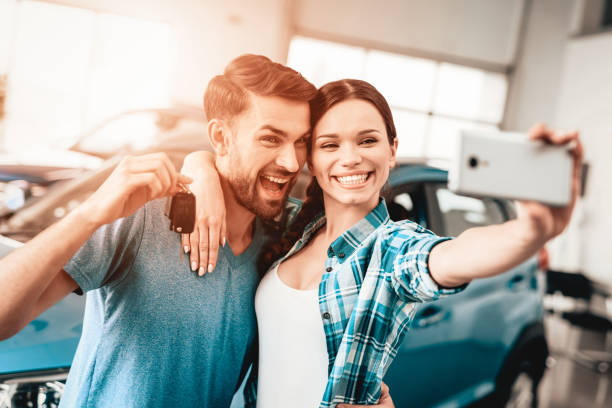 un hombre y una mujer hacen selfie cerca de su coche nuevo. - tipo de transporte fotos fotografías e imágenes de stock