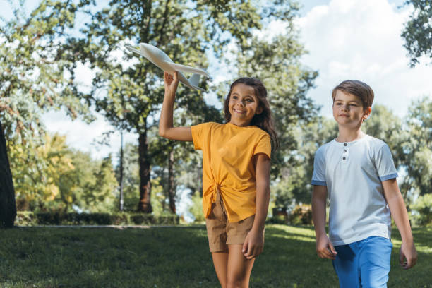 istock cute smiling children playing with plane model in park 1032585312