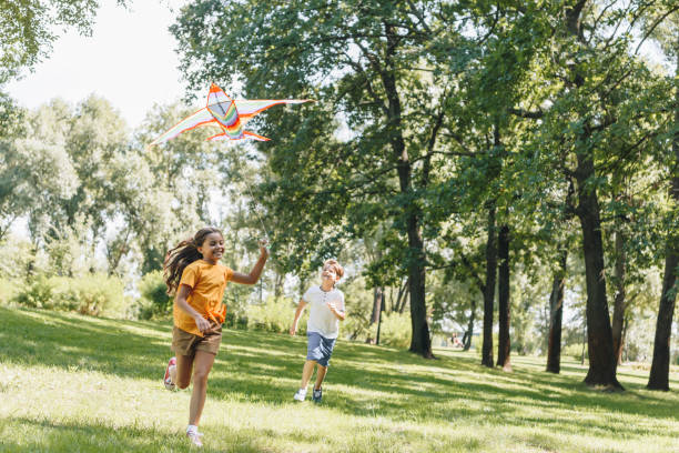 istock cute happy kids playing with colorful kite in park 1032585480