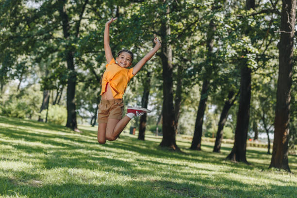 istock cute cheerful kid jumping and smiling at camera in park 1032585670