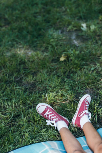 low section of child resting on green grass in park