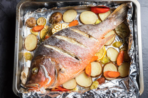 pesce dentice rosso sostenuto dal forno con verdure, appena dal forno, pronto da mangiare - prepared fish prepared snapper freshness roasted foto e immagini stock
