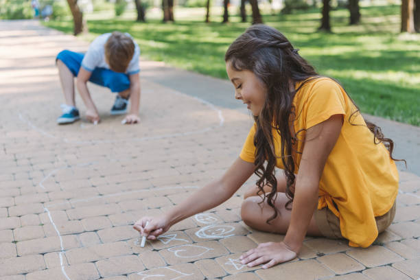 istock adorable smiling children drawing with chalk in park 1032586310
