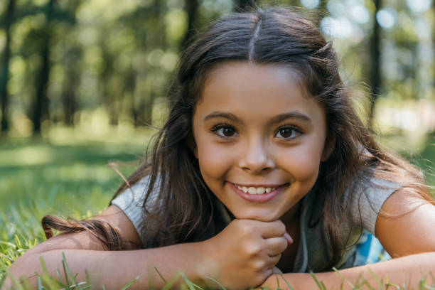 istock adorable happy child lying on grass and smiling at camera in park 1032586388