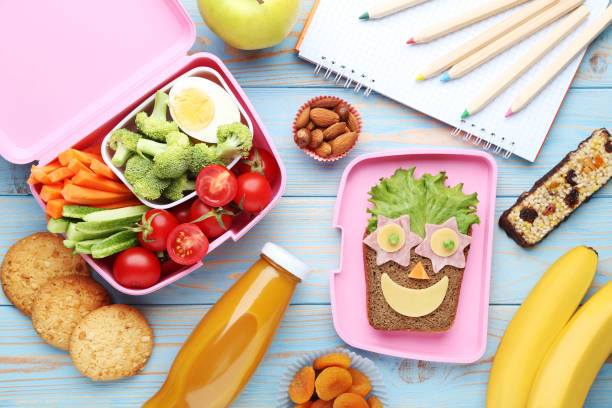 school lunch box with vegetables and fruits on blue wooden table - lunch box lunch red apple imagens e fotografias de stock