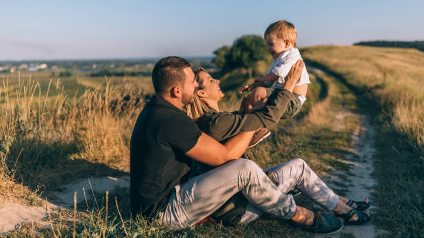 istock smiling young parents playing with adorable little son while sitting together on rural trail 1032596324