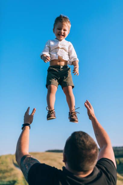istock father throwing up adorable happy little son against blue sky 1032596362