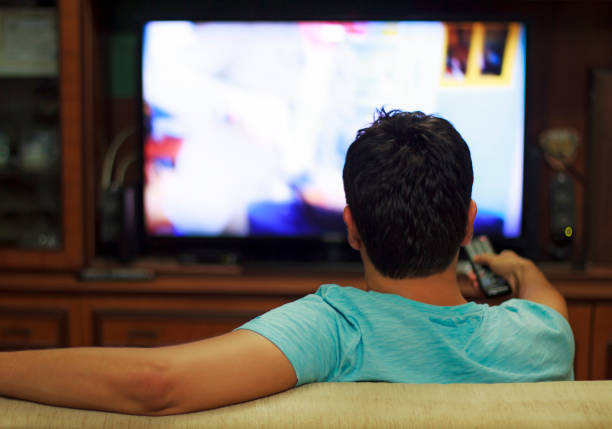 hombre viendo la televisión en casa sala de estar / canal de salto - television commercial fotografías e imágenes de stock