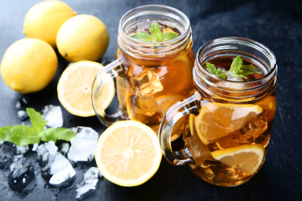 istock Ice tea in glass jars with lemon and mint leafs on wooden table 1032608194