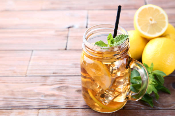 istock Ice tea in glass jar with lemon and mint leafs on wooden table 1032608612