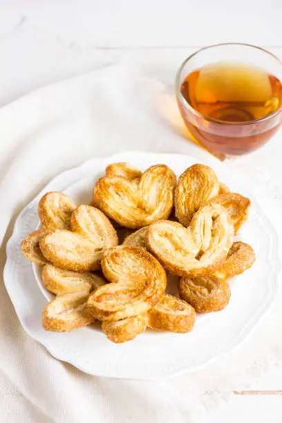 Puff pastry hearts on a white plate with a Cup of tea