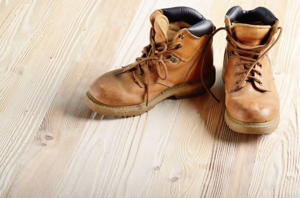 istock Yellow leather used work boots on wooden background closeup. Place for text 1032609816