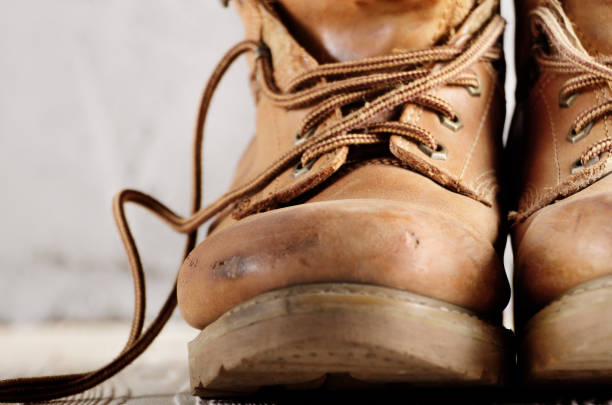 istock Yellow leather used work boots on concrete background closeup. Place for text 1032609874