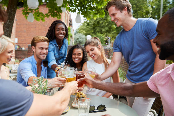 istock Friends Sitting At Table In Pub Garden Making Toast Together 1032610494