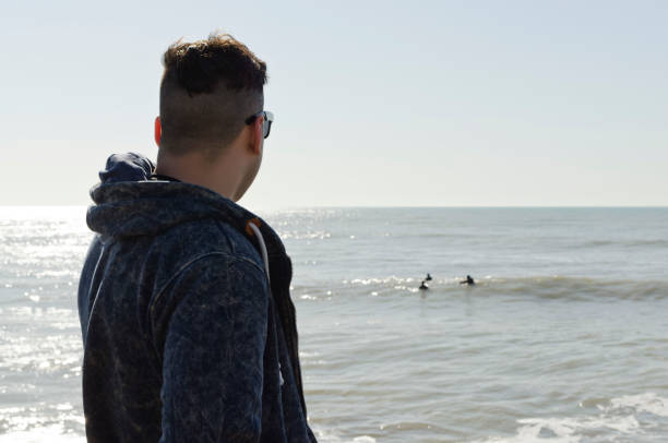 istock young man walking on the beach on a sunny day 1032612988