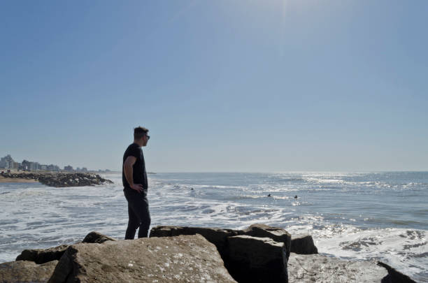 istock young man walking on the beach on a sunny day 1032613350