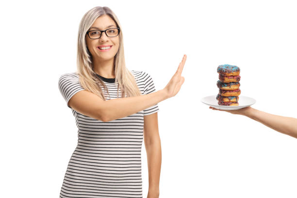 молодая женщина отказывается тарелку пончиков - dieting food rejection women стоковые фото и изображения