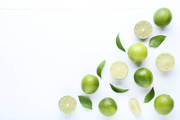 istock Ripe limes with green leafs on white wooden table 1032614370