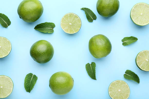 istock Ripe limes with green leafs on blue background 1032614684