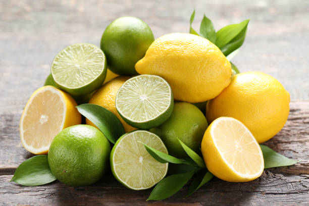 istock Lemons and limes with green leafs on grey wooden table 1032617014