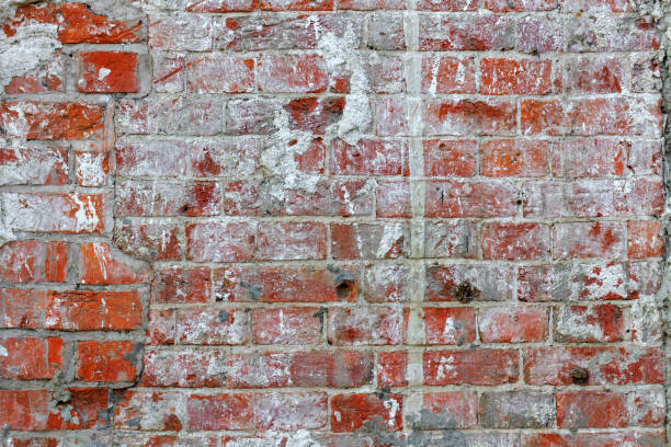 istock Weathered dirty red brick wall texture with cracks and paint stains. Abstract brick wall background 1032628130