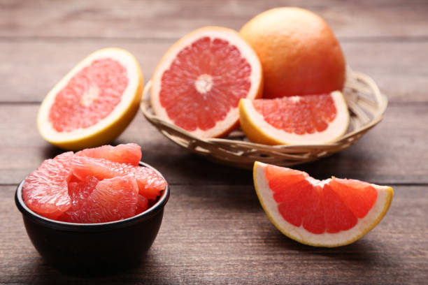 toronjas maduras en canasta y el tazón en la mesa de madera marrón - pomelo fotografías e imágenes de stock