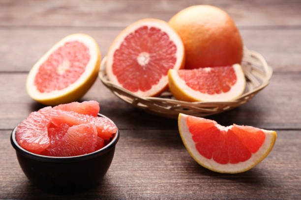 Ripe grapefruits in basket and bowl on brown wooden table Ripe grapefruits in basket and bowl on brown wooden table grapefruit photos stock pictures, royalty-free photos & images