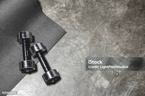 Top View Of Yoga Mat And Dumbbells Lying On Concrete Surface Stock Photo - Download Image Now