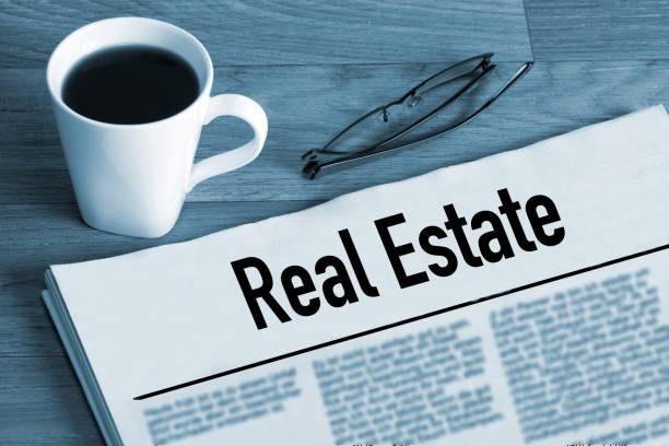 A cup of coffee, reading glasses and a newspaper titled Real Estate stock photo