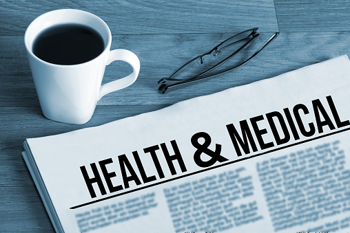 A cup of coffee, glasses and newspaper titled Health Medical