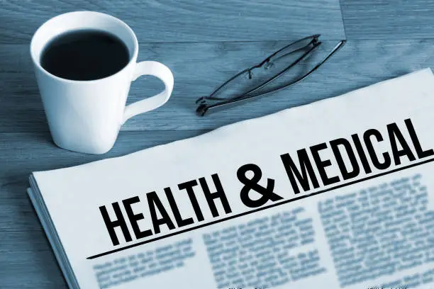 A cup of coffee, glasses and newspaper titled Health Medical