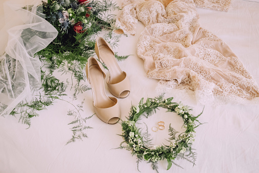 wedding morning composition of the great wedding bouquet wedding dress wreath shoes on bed
