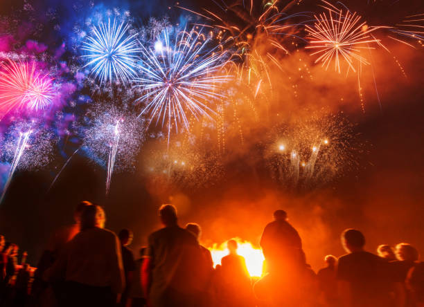 persone in piedi di fronte a colorate opere d'artificio - firework display foto e immagini stock