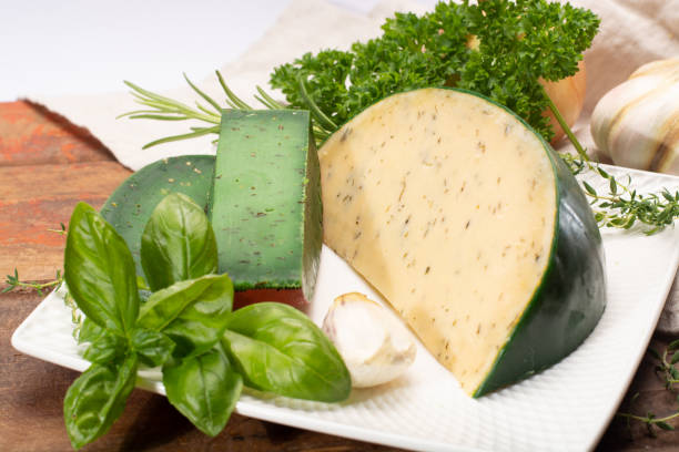 fromage à pâte dure spécialité néerlandaise fait de lait de vaches avec différentes épices et herbes vertes fraîches - basiron photos et images de collection