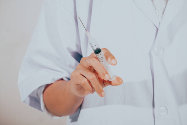 istock Midsection Of Doctor Holding Syringe Against White Background 1032656556
