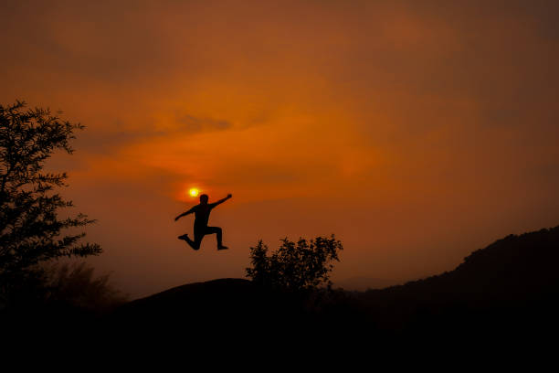 istock Silhouette Man Jumping On Field Against Orange Sky 1032656642