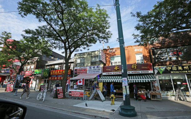 Toronto, Canada - August 24, 2018: Shoppers stroll past the colorful, multilingual signs on the 200-block Spadina Avenue. Summer afternoon in the Grange Park neighbourhood of Downtown.